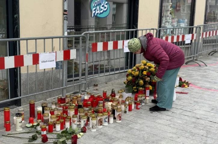 Fleurs et bougies sont déposées 
en mémoire des victimes de l'attaque au couteau perpétrée par un demandeur d'asile syrien, qui a coûté la vie à un adolescent et blessé cinq autres personnes, le 16 février 2025 à Villach, dans le sud de l'Autriche
