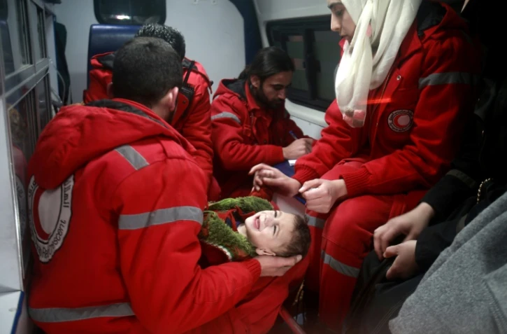 Du personnel du Croissant Rouge syrien évacue un enfant de Douma, dans la Ghouta orientale assiégée par le régime de Damas, le 26 décembre 2017  