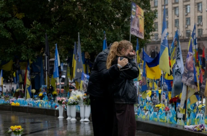 Des passants devant un mémorial improvisé pour les soldats ukrainiens et étrangers morts au combat, le 7 octobre 2025 à Kiev 
