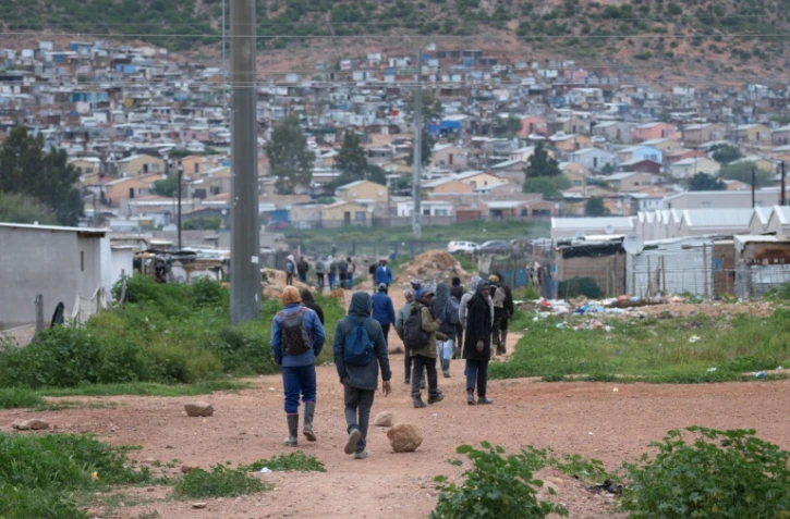 Des travailleurs, pour la plupart employés dans des fermes locales, rentrent chez eux à Nkqubela, un township et campement informel de la ville de Robertson (province du Cap-Occidental, Afrique du Sud), le 9 juillet 2026