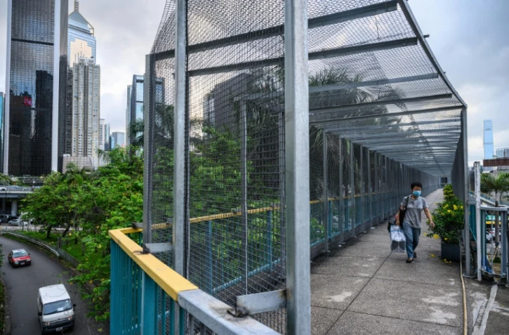Un habitant de Hong Kong emprunte le 3 juin 2020 une passerelle recouverte de grillage, édifiée par les autorités locales en réponse aux manifestations pro-démocratie.
