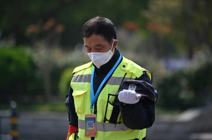 Un policier se fige lors des 3 minutes de silence en mémoire des morts du Covid-19, le 4 avril 2020 à Wuhan 