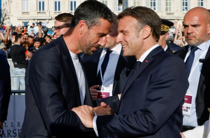 Le patron du comité d'organisation de Paris 2024 Tony Estanguet (G) serre la main du président Emmanuel Macron à l'arrivée de la flamme olympique à Marseille le 8 mai 2024