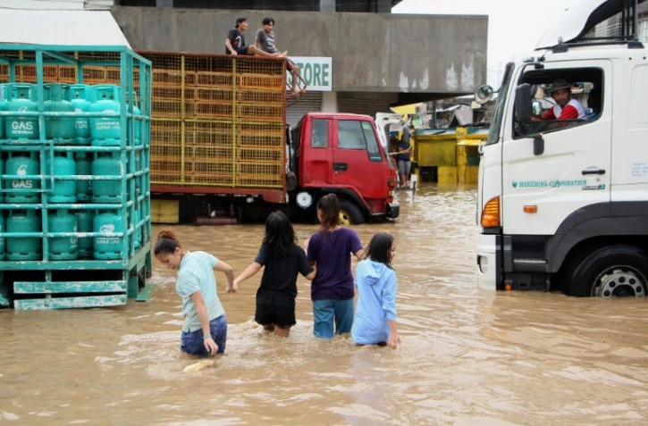 Des habitants de la ville de Baao marchent les rues inondĂ©es aprĂšs le passage de la tempĂȘte Usman, le 30 dĂ©cembre 2018