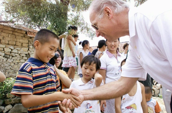 Joe Biden, alors chef de la commission des affaires étrangères du Sénat salue un enfant du village de  Yanzikou, le 10 août 2001