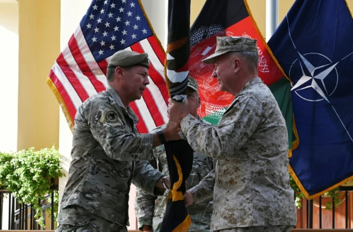 Le général Austin Scott Miller (G), chef des forces américaines en Afghanistan, remet le drapeau de la mission de l'Otan dans le pays au général Kenneth McKenzie, chef du Commandement central américain (Centcom) lors d'une cérémonie à Kaboul, le 12 juillet 2021