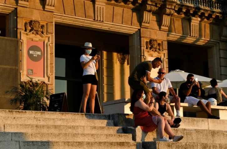 Des visiteurs assis devant le musée national d'art de Barcelone le 25 juillet 2020