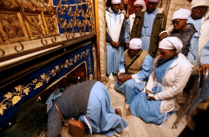 Des pèlerins nigérians prient la veille de Noël sur le lieu de naissance présumé de Jésus, dans la basilique de la Nativité à Bethléem en Cisjordanie, le 24 décembre 2018