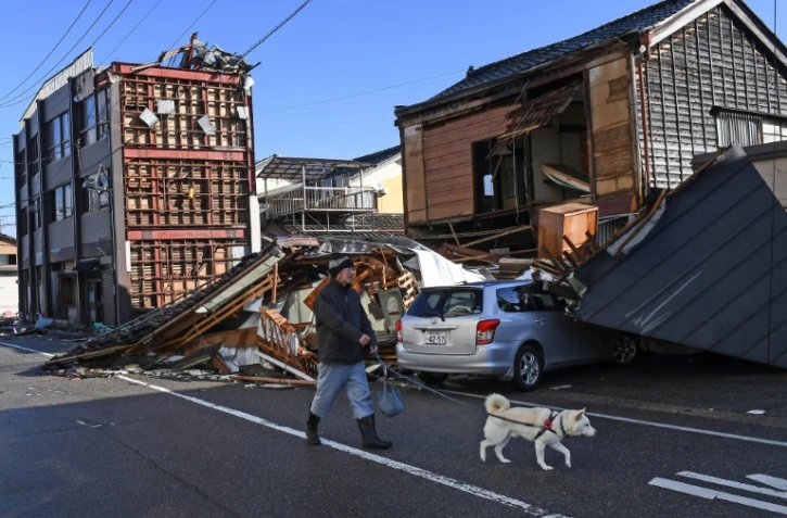 Un homme promène son chien à Anamizu dans le département d'Ishikawa le 4 janvier 2024 après le séisme du Nouvel An