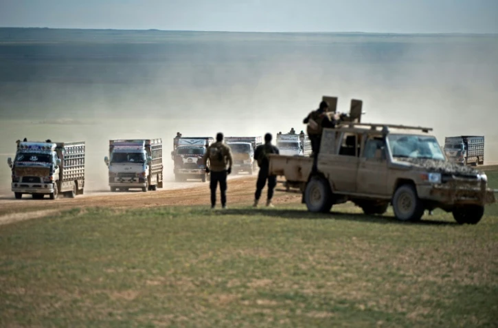 Des combattants des Forces démocratiques syriennes (FDS) surveillent un convoi de civils fuyant le dernier réduit du groupe jihadiste Etat islamique dans l'est de la Syrie, le 11 février 2019 