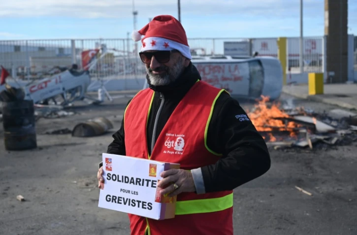 Un militant CGT porte une cagnotte pour les grévistes, lors d'un repas de noël organisé le 24 décembre 2019 au port de Marseille