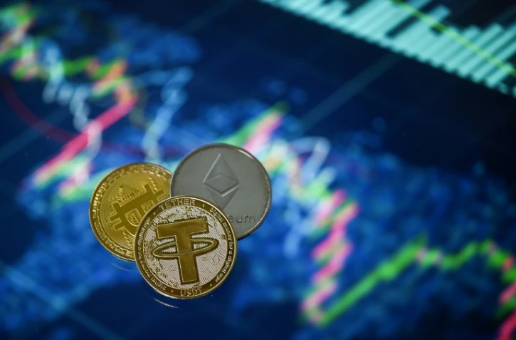 Des pièces souvenir reproduisant les logos du Tether, du bitcoin et de l'Ethereum photographiées à Londres, le 8 mai 2022