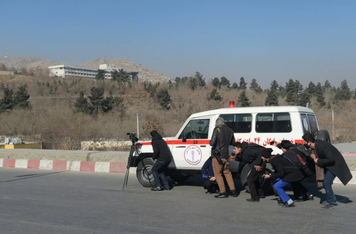 Des journalistes afghans se refugiant derrière une ambulance à Kaboul le 21 janvier 2018