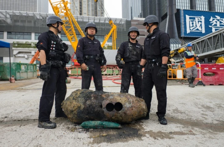 Des démineurs posent devant une bombe de la Seconde Guerre mondiale découverte sur un chantier de construction à Hong Kong, le 11 mai 2018
