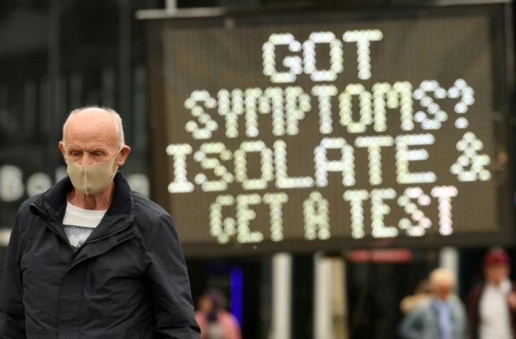 Un panneau d’affichage enjoint au public la conduite à tenir en cas de symptômes du covid 19, à Bolton, en Angleterre, le 28 mai 2021