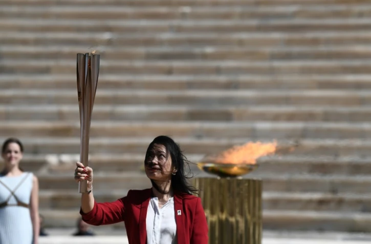 L'ex-championne japonaise de natation Imoto Naoko brandit la flamme olympique qu'elle vient de recevoir des autorités grecques à Athènes, le 19 mars 2020 