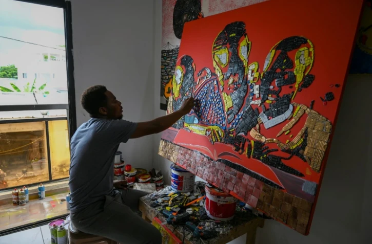 L'artiste vorien Mounou Désiré Koffi réalise une toile avec des claviers de téléphone usagés dans sa résidence de Bingerville, une commune d'Abidjan, le 28 avril 2022