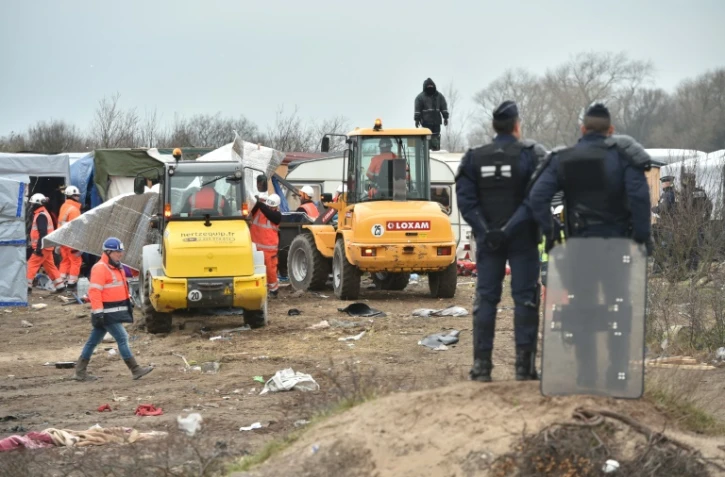 Des policiers surveillent le démantèlement d'abris dans la "jungle" de Calais par des bulldozers, le 1er mars 2016