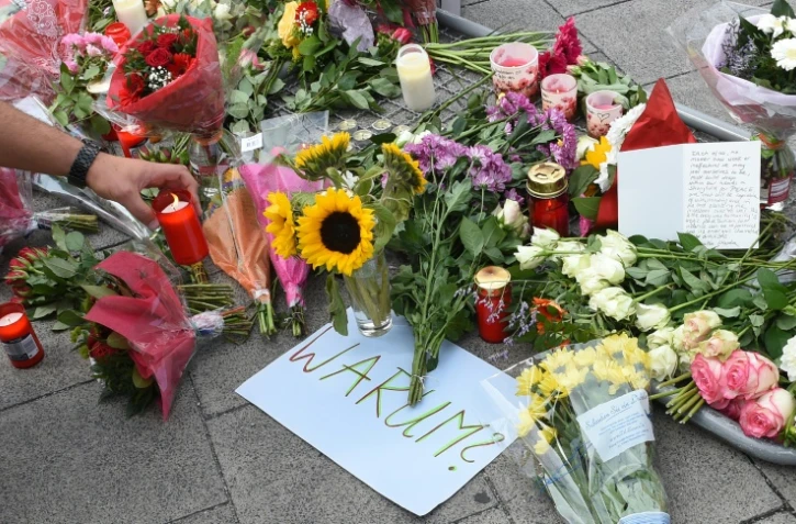 Bougies, fleurs et note où est inscrit "Pourquoi" rendent hommage aux neuf victimes du forcené, à l'entrée du centre commercial de Munich le 23 juillet 2016