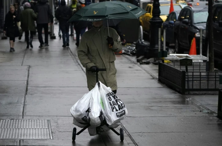 Un homme marche avec un chariot de sacs en plastique contenant ses courses le 28 février 2020 à Manhattan
