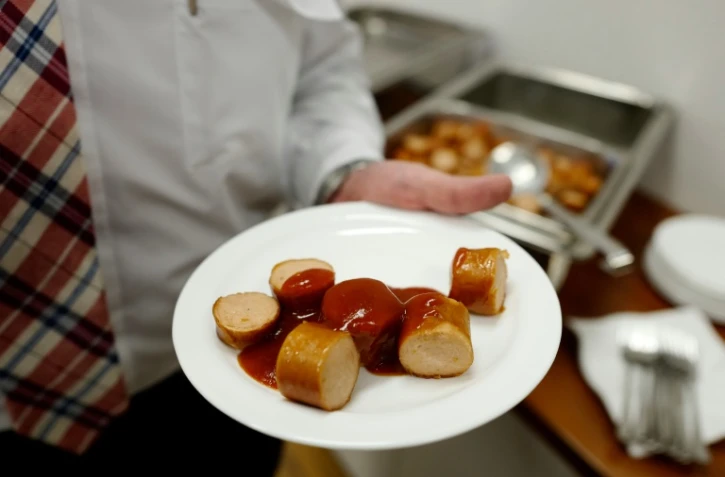 Un employé du constructeur automobile allemand Volkswagen tente une assiette de currywurst (saucisse au curry), au siège de l'entreprise à Wolfsburg en Allemagne le 21 avril 2016