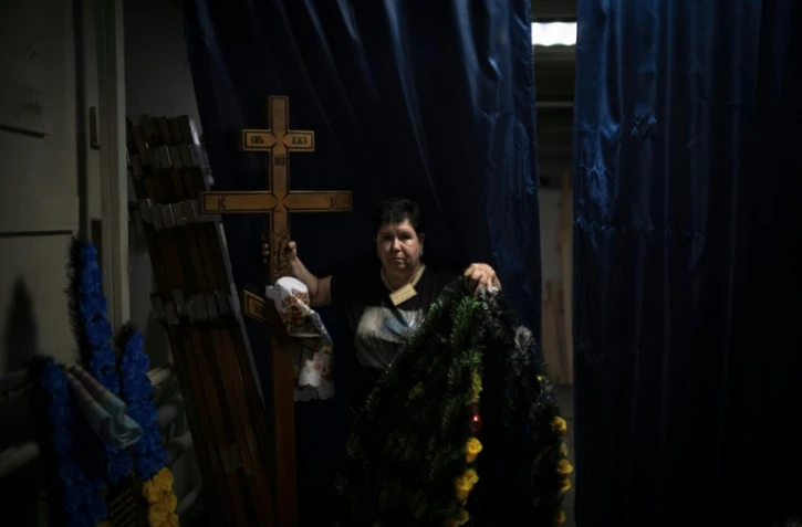 Svitlana Ostapenko, gérante du funérarium de Sumy, dans le nord-est de l'Ukraine, prépare, le 11 juin 2025, une croix et un couronne mortuaire pour l'enterrement d'un jeune soldat tué récemment lors de combats contre les forces russes