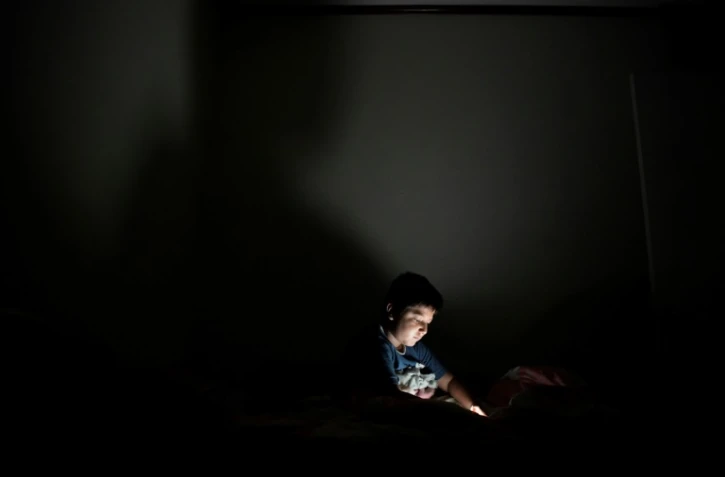 Un enfant joue sur un smartphone dans sa chambre à San Salvador en octobre 2018