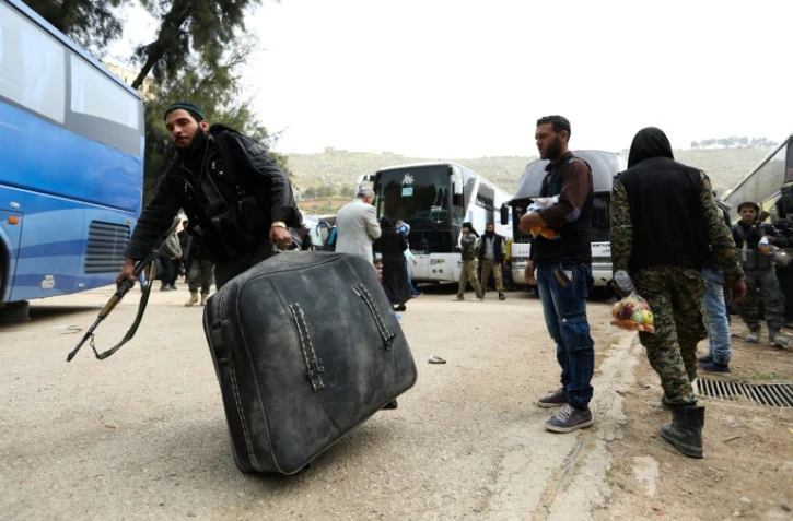 Des civils syriens et combattants rebelles arrivent dans le village de Qalaat al-Madiq, au nord de Hama, après avoir été évacués de Harasta située dans la Ghouta orientale, le 24 mars 2018