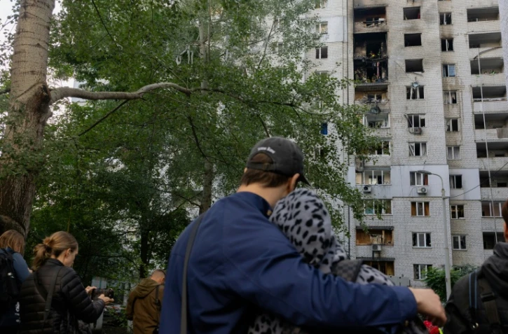 Des habitants observent un immeuble résidentiel endommagé après une frappe de drone russe à Kiev, le 25 septembre 2026