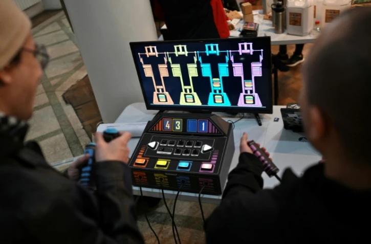 Des personnes jouent à un jeu vidéo fabriqué à partir de composants électroniques recyclés lors de la 3e Rencontre fédérale Cyberciruja à Buenos Aires, le 16 août 2025 en Argentine