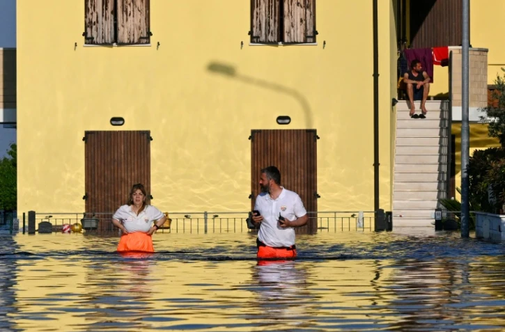 Des sauveteurs dans une rue inondée de Conselice, près de Ravenne, le 21 mai 2023, après que des inondations meurtrières ont frappé la région d'Émilie-Romagne, en Italie