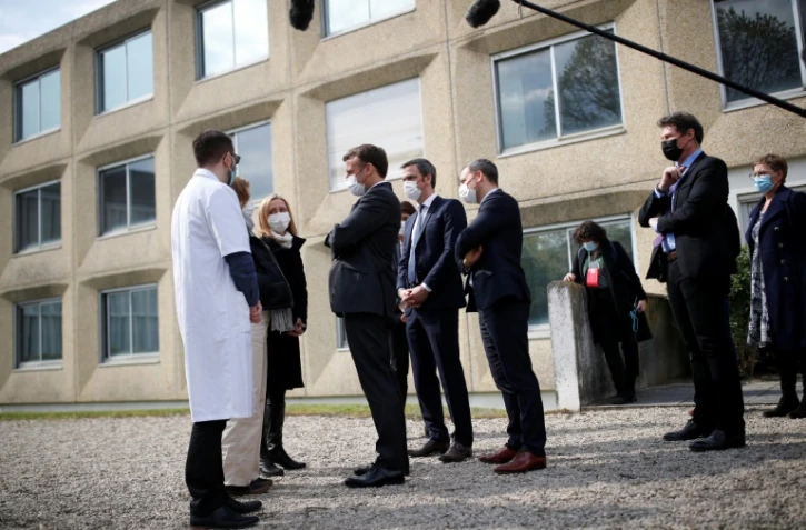 Le président français Emmanuel Macron (c) parle à des soignants lors d'une visite au service pédopsychiatrique du CHU de Reims, le 14 avril 2021