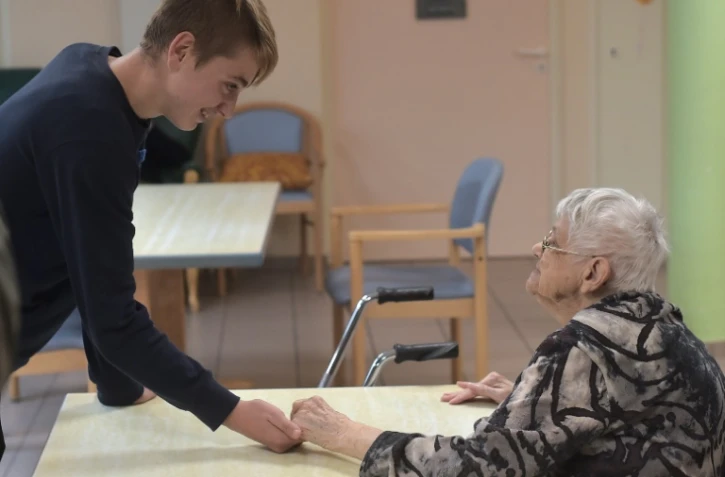 Un adolescent tient la main d'une patiente atteinte de la maladie d'Alzheimer le 18 octobre 2016 à Saint-Quirin dans l'est