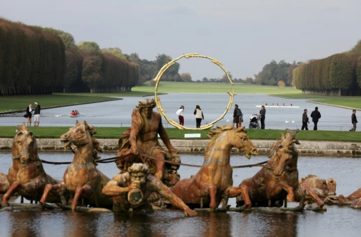 Des visiteurs marchent dans les jardins de Versailles, passant devant une sculpture de l'artiste suisse Ugo Rondinone, le 19 octobre 2017
