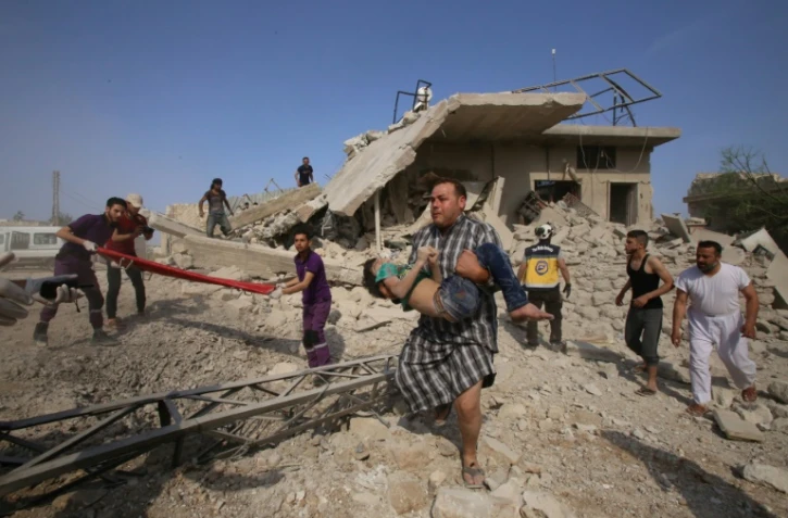 Un homme transporte un enfant dans la localité  de Maaret al-Noomane dans la province d'Idleb en Syrie, où des secouristes cherchent des survivants dans les décombres après une frappe aérienne du régime syrien et son allié russe selon une ONG, le 30 mai 2019