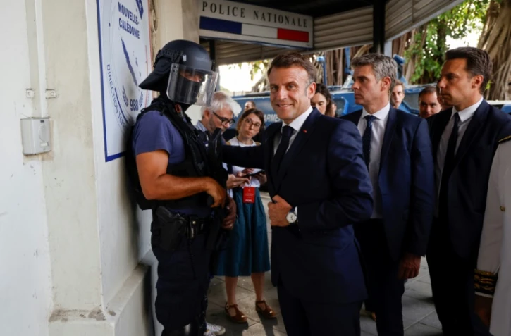 Le président français Emmanuel Macron (C) arrive au commissariat central de Nouméa, en Nouvelle-Calédonie, le 23 mai 2024