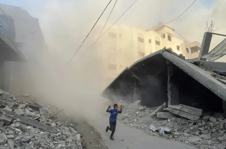 Un garçon palestinien fuit en courant des frappes aériennes à Jabalia, dans le nord de la bande de Gaza, le 19 août 2025
