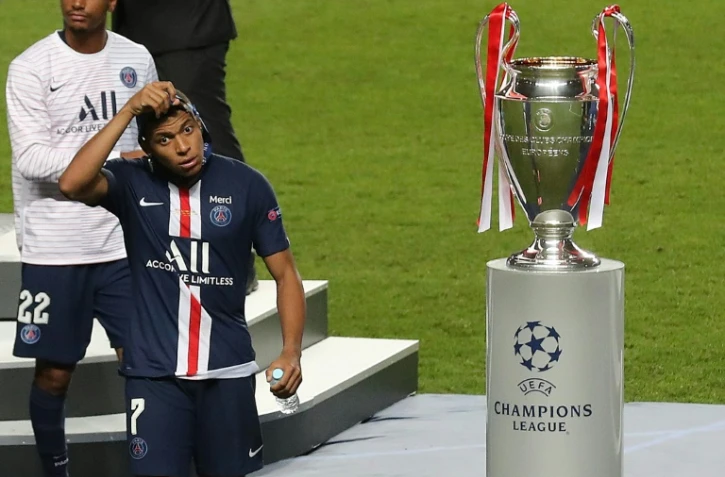L'attaquant du Paris Saint-Germain Kylian Mbappé enlève sa médaille de finaliste en passant à côté du trophée de vainqueur de la Ligue des champions après la défaite en finale contre le Bayern Munich le 23 août 2020 à Lisbonne