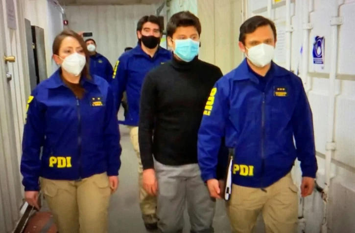 Nicolas Zepeda (en noir) est excorté par la police chilienne à son arrivée à l'aéroport de Santiago, le 23 juillet 2020.