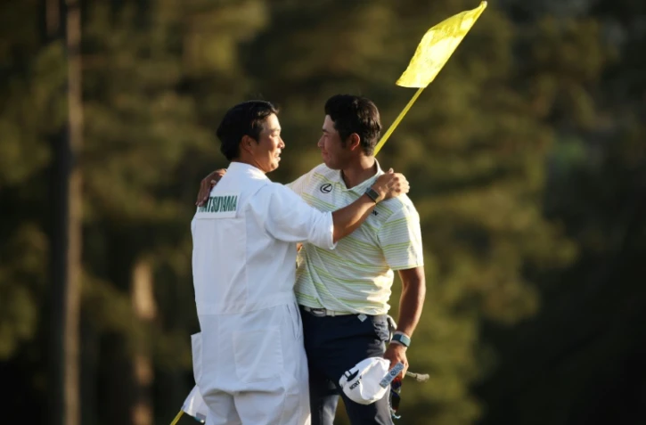 photo d'archives prise le 10 avril 2021 montrant le golfeur japonais Hideki Matsuyama, avec son caddie Shota Hayafuji, sur le green du 18ème trou après avoir remporté le Masters à Augusta, Géorgie, le 11 avril 2021