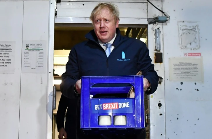 Le Premier ministre Boris Johnson porte un pack de bouteilles de lait  à Guiseley, dans le cadre de sa campagne électorale le 11 décembre 2019