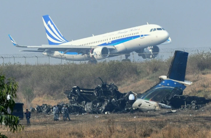 Décollage de l'aéroport international de Katmandou le 13 mars 2018, non loin de l'épave de l'avion de la compagnie bangladaise US-Bangla, qui s'est écrasé lundi à Katmandou faisant 49 morts