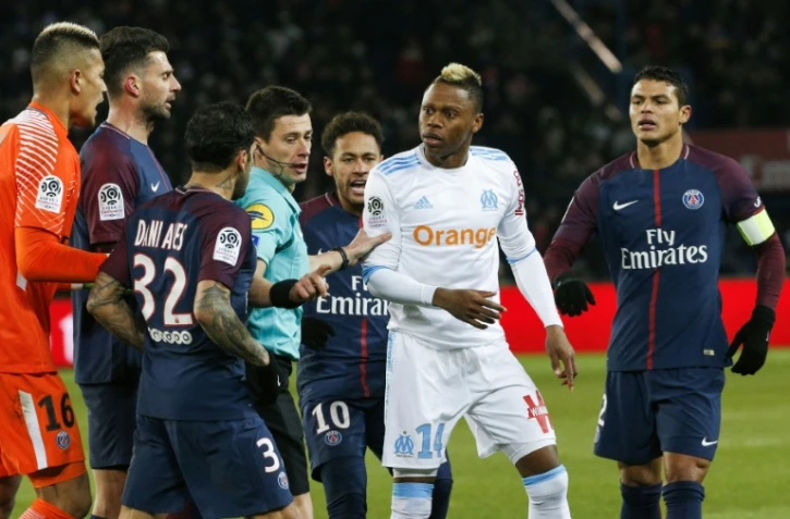 L'attaquant marseillais Clinton Mua Njie (2ndR) discutant avec le défenseur du Paris SG, Dani Alves, à la droite de l'arbitre, au cours du match opposant le PSG à Marseille, le 25 février 2018 au Parc des Princes, à Paris