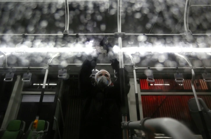Un employé municipal pulvérise du désinfectant dans un bus pendant une épidémie de Covid-19, le 26 février 2020 à Téhéran, en Iran