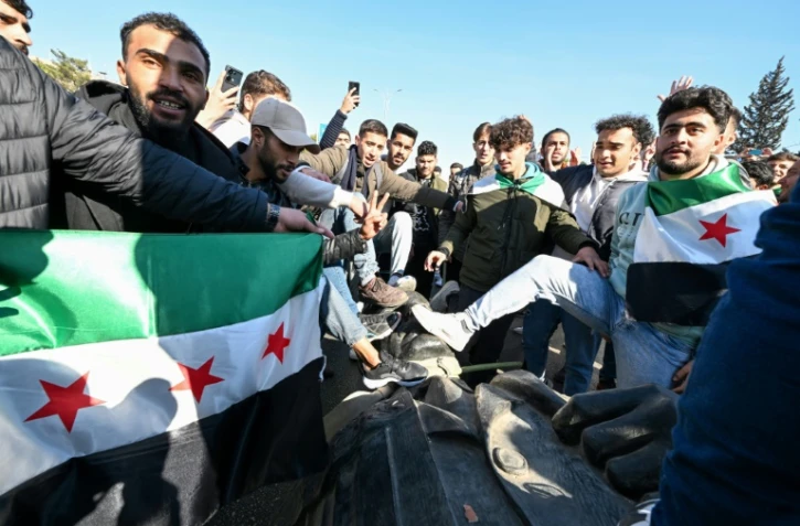 Des étudiants traînent la statue de l'ancien président Hafez al-Assad près du campus de l'université de Damas, le 15 décembre 2024 en Syrie