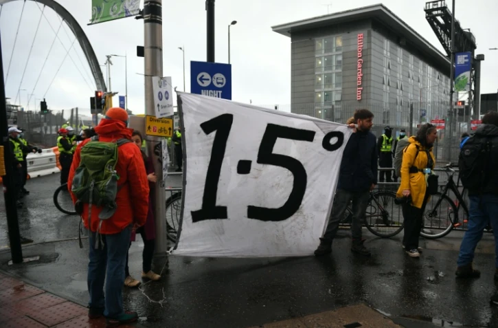 Des manifestants autour d'une banderole appelant à limiter le réchauffement de la planète à +1,5°, en marge de la COP26, à Glagow, en Ecosse