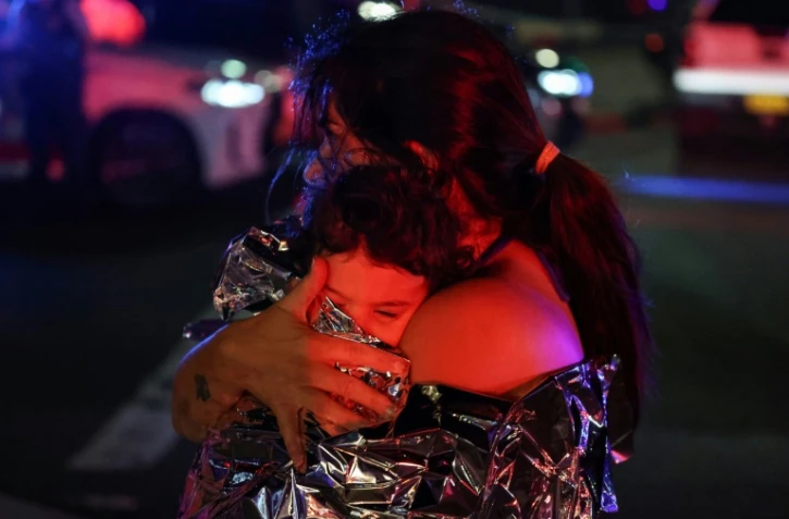 Une mère enveloppée avec son enfant dans une couverture de survie après l'attaque contre une fête juive sur la plage de Bondi, à Sydney, qui a fait onze morts et 29 blessés, le 14 décembre 2025