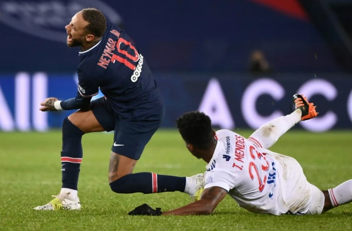 L'attaquant brésilien du Paris Saint-Germain, Neymar, taclé par son compatriote de Lyon, le milieu de terrain Thiago Mendes, lors de leur match de L1, le 13 décembre 2020 au Parc des Princes