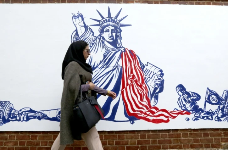 Une Iranienne passe devant une fresque murale sur l'enceinte de l'ancienne ambassade américaine à Téhéran, le 2 novembre 2019
