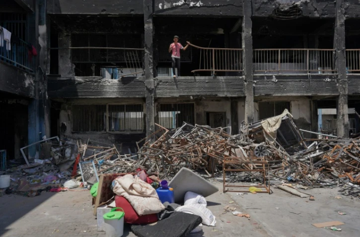 Des déplacés palestiniens déblaient les décombres d'un bâtiment endommagé à Khan Younès, dans le sud de la bande de Gaza, le 9 mai 2024 